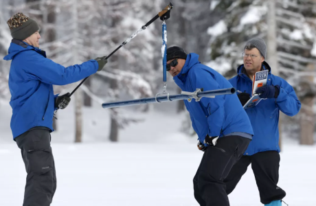 three men in blue jackets in deep snow