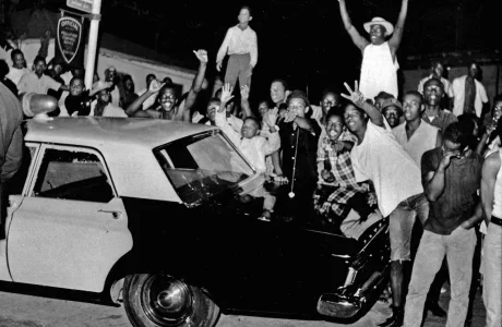 In this Aug. 12, 1965 file photo, demonstrators push against a police car after rioting erupted in the Watts district of Los Angeles. It began with a routine traffic stop 50 years ago this month, blossomed into a protest with the help of a rumor and escalated into the deadliest and most destructive riot Los Angeles had seen. The Watts riot broke out Aug. 11, 1965 and raged for most of a week. When the smoke cleared, 34 people were dead, more than a 1,000 were injured and some 600 buildings were damaged.