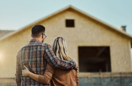 Rear view of an embraced couple looking at built structure from outside.