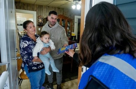 man, woman, baby at front door speaking with election worker