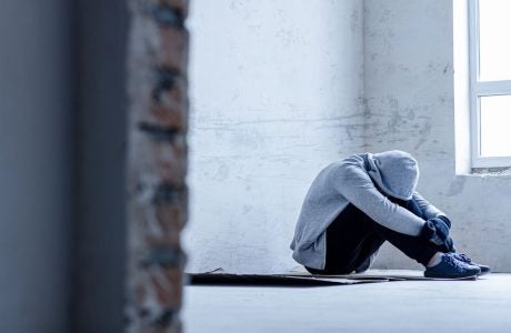 young man in gray hooded seated and bent over