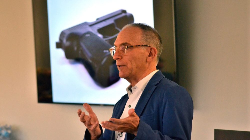 Professor Mark Kaplan speaks in class about firearm suicides and behind him is an image of a gun on the projector.