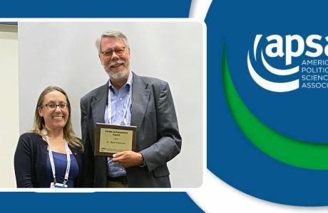 Photo of professor Mark Peter holding the Career Achievement Award with Julianna Pacheco who presented the award.