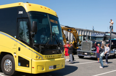 yellow bus greeted by people waving and taking pictures