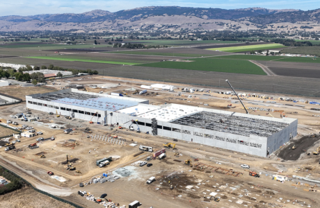 large concrete building being constructed in agricultural setting