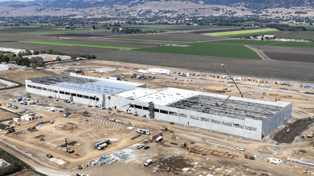 large concrete building being constructed in agricultural setting