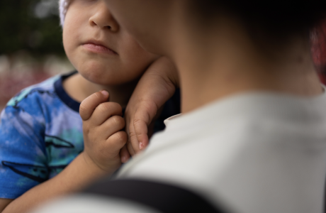 young child with face only partially shown held by adult