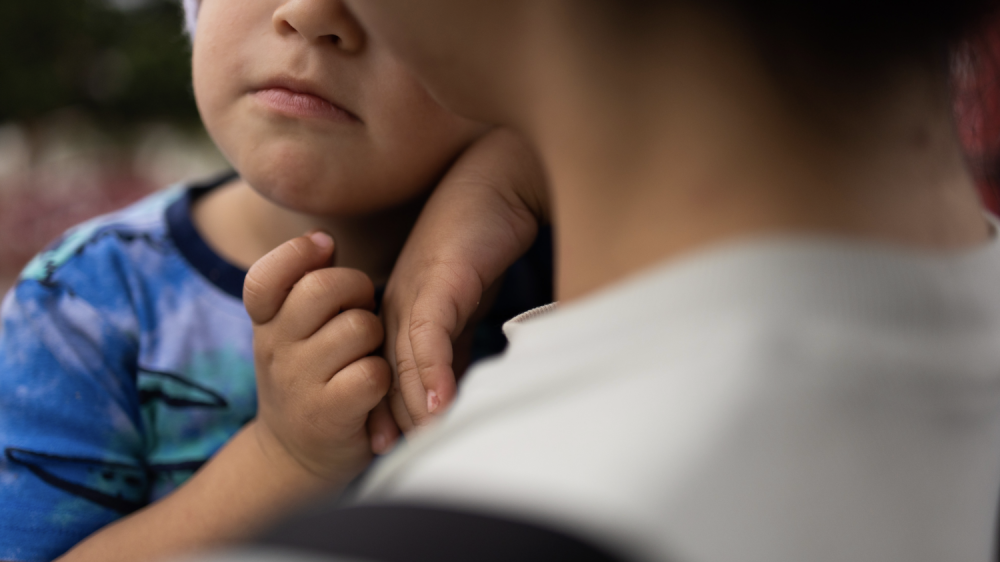 young child with face only partially shown held by adult