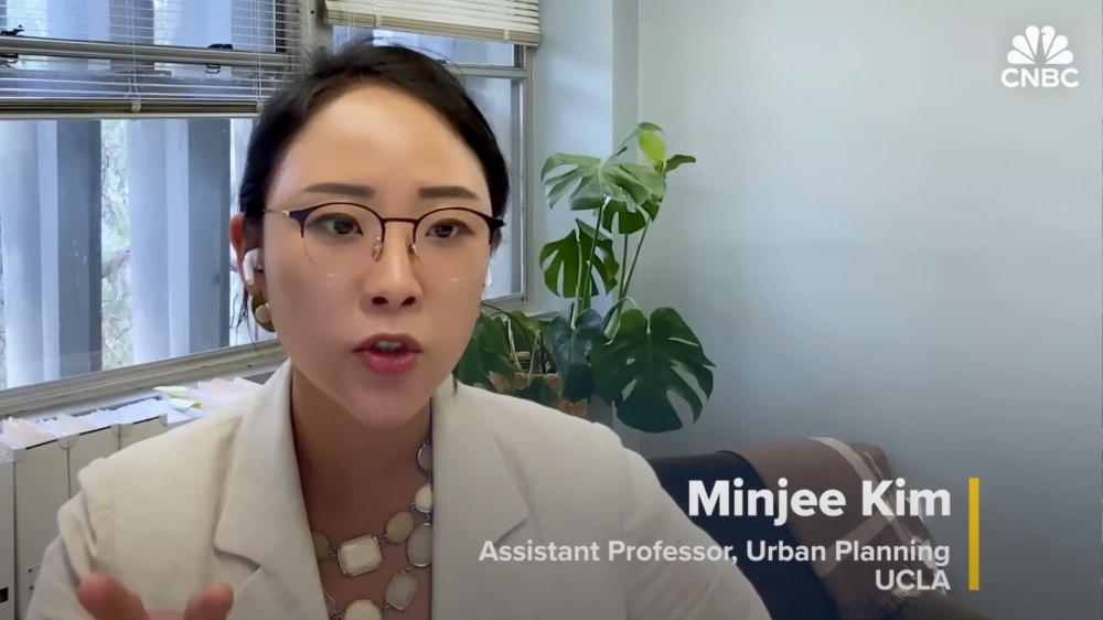 Dr. Minjee Kim sits in her office being interviewed via Zoom for a CNBC feature on the rise of gated communities in the U.S.