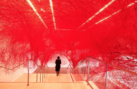 woman in museum lobby adorned with red yarn