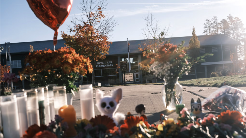 flowers, candles, stuffed animals with school building in background