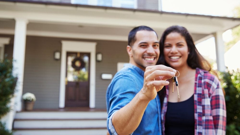 male and female holding up a key to their new home standing in front of the house they just purchased.|Professor of Urban Planning Jose Loya Smiles, standing in front of Public Affairs building||Professor of Urban Planning Jose Loya Smiles, standing in front of Public Affairs building||Jose Loya smiles in front of the Meyer and Renee Luskin Public Affairs Building.|Jose Loya stands smiling in front of the Public Affairs building at UCLA.