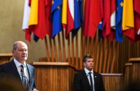Two men in suits with flags in the background