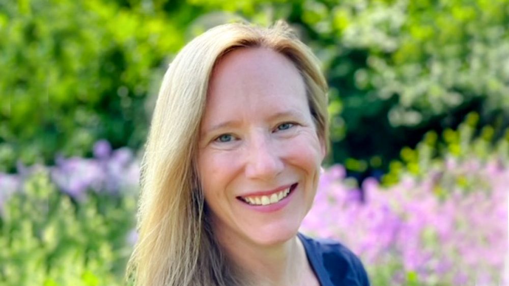 photo of woman with blond hair in front of flowering plants
