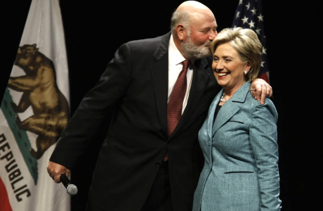 Man in suit embraces woman in suit on stage