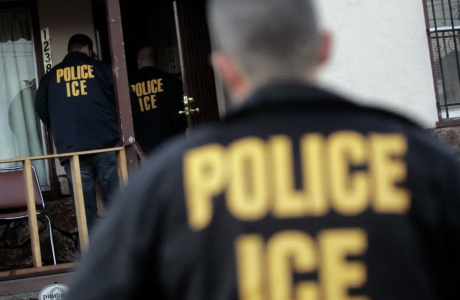 Officers in jackets that say " Police, ICE" enter a house