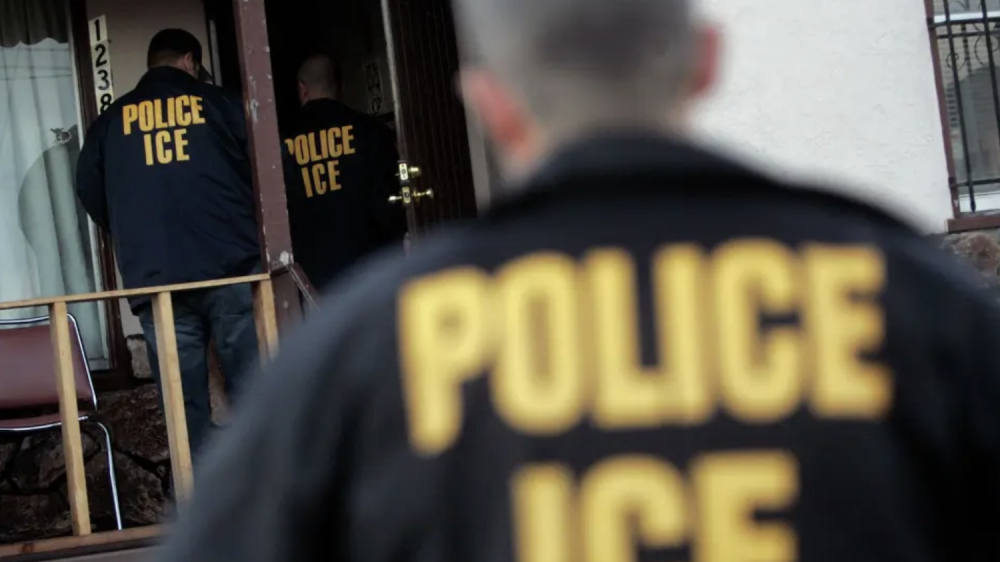 Officers in jackets that say " Police, ICE" enter a house