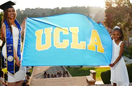 Schinal Harrington holds up a UCLA flag on her graduation day with her young daughter.|Schinal Harrington and Daughter Desi stand and pose with book "Social Justice Parenting"|Photo of Schinal's young daughter kissing Schinal Harrington, MSW, and parenting student on the forehead.
