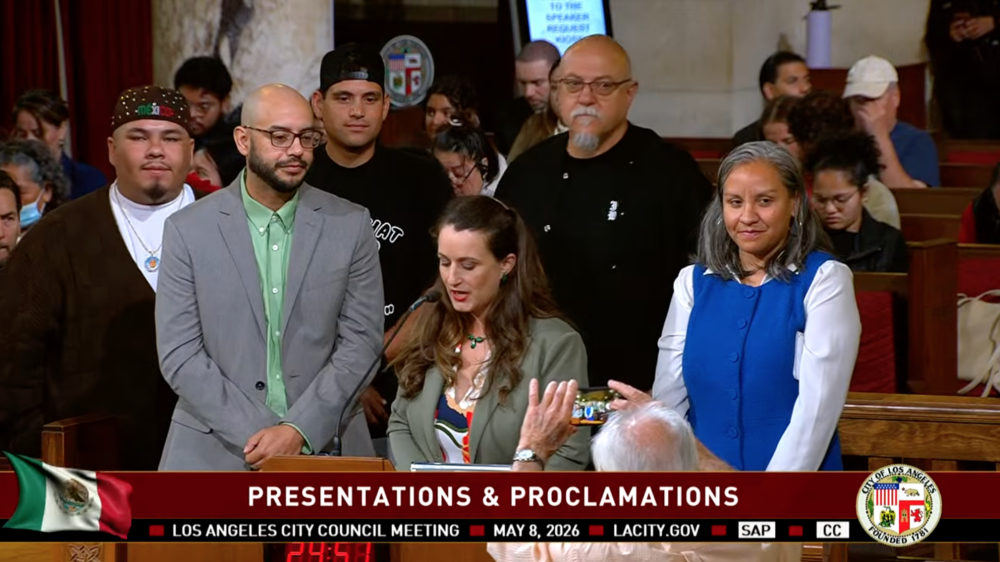 Los Angeles City Council Meeting on May 8, a speaker presents José Loya and Amada Armenta with their "impactful chicanos" award at City Hall.|Two photos next to each other, on the left is Jose Loya and Amada Armenta holding up their "Impactful Chicanos" awards inside City Hall, the photo on the right is of Jose and Amada standing next to a framed illustration of UCLA Latino Policy and Politics Institute.