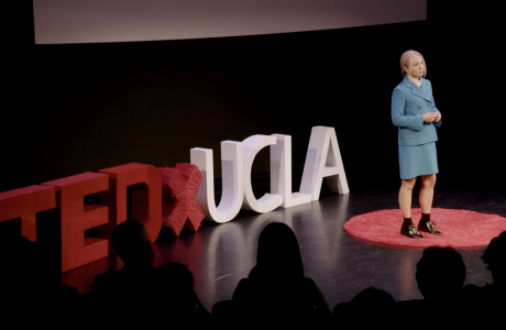 Kelly Turner TedXUCLA talk screenshot with her on a black stage in a blue blazer and skirt.