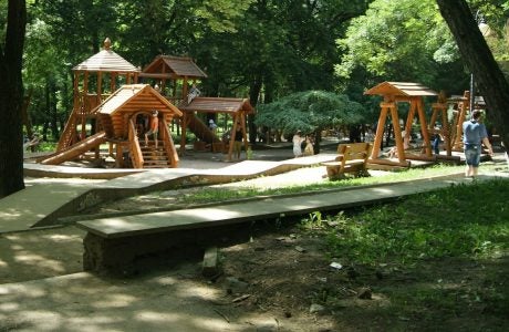 Shaded playground with wooden play equipment for kids