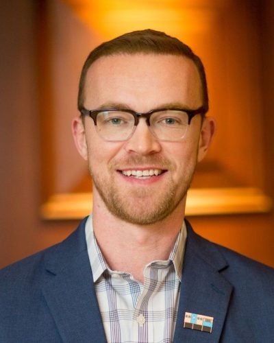 Man with glasses and beard wearing a blue blazer