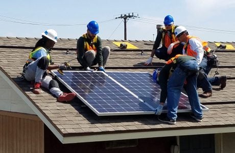 Diana Adams, installation supervisor at GRID Alternatives, instructs trainees and residents of LINC Housing’s City Gardens property in Santa Ana on how to properly set and secure solar panels. Photo by GRID Alternatives
