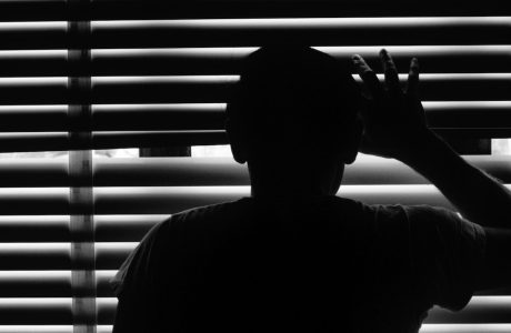 silhoutette of person looking through window blinds
