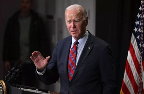 Man in suit and tie at podium next to American flag
