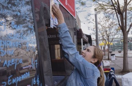 Woman putting up sign on food stand