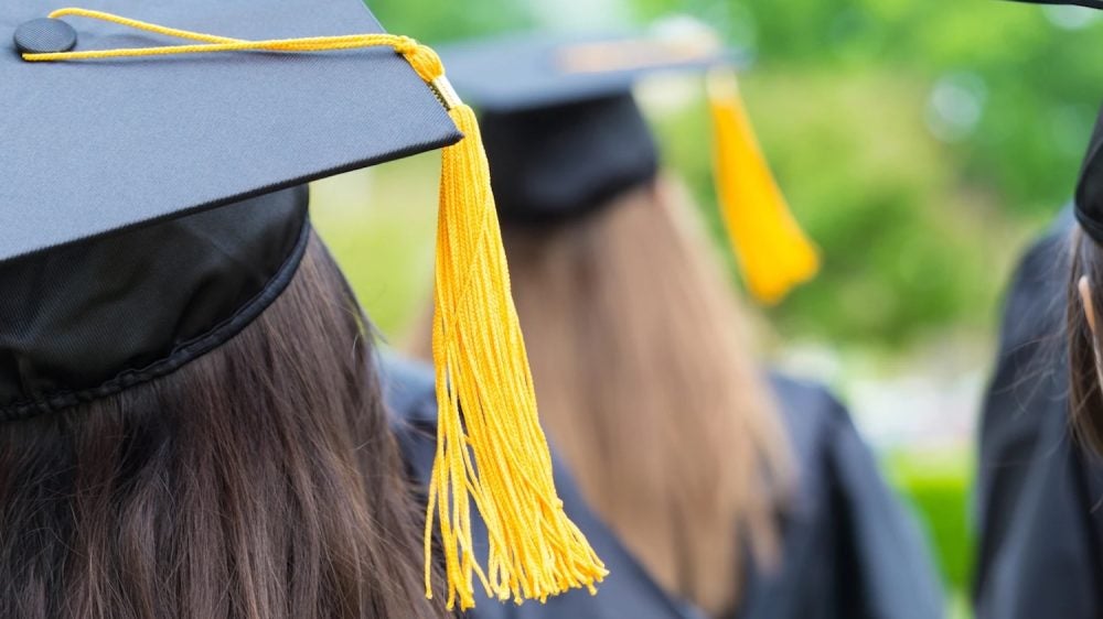 back of student's head with graduation cap and yellow tassel