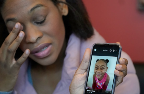Woman holding phone showing picture of little girl