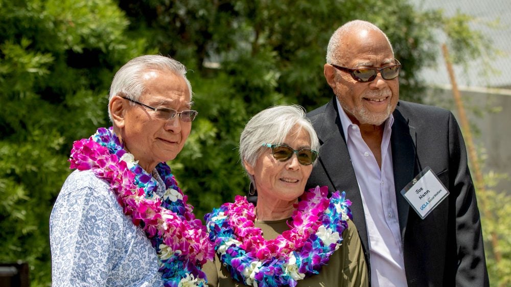 three people outdoors, two wearing leis|three young people in historic B&W photo