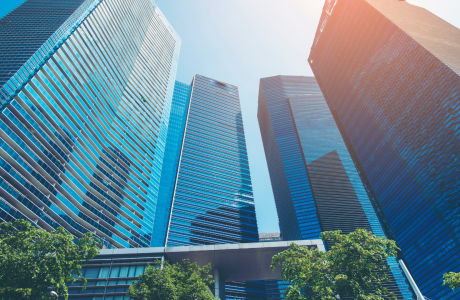 A photo of tall skycrapers coming a semi circle on a bright sunny day with the shadow of some of the building being cast on a few.