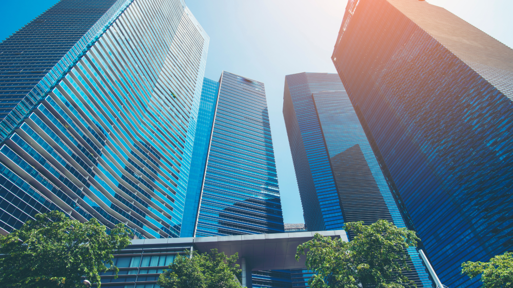 A photo of tall skycrapers coming a semi circle on a bright sunny day with the shadow of some of the building being cast on a few.