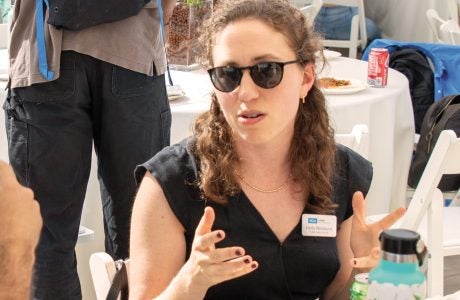 woman in sunglasses gestures while seated an event