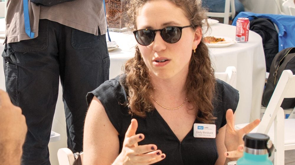 woman in sunglasses gestures while seated an event