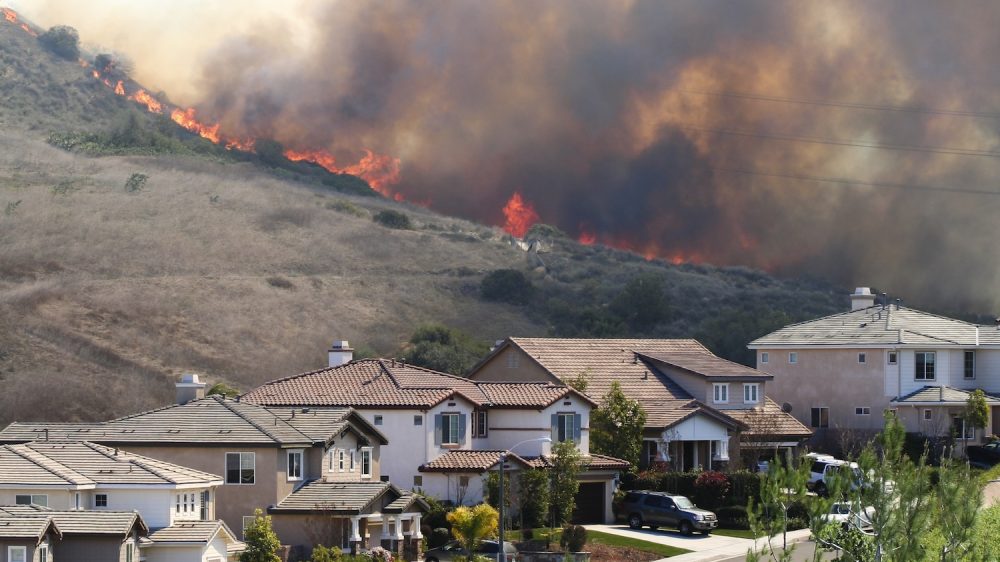 Flames on ridge in back of street with two-story houses