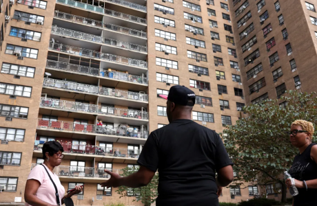 three people outside large apartment complex