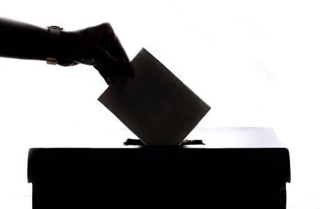silhouette of hand placing ballot in box