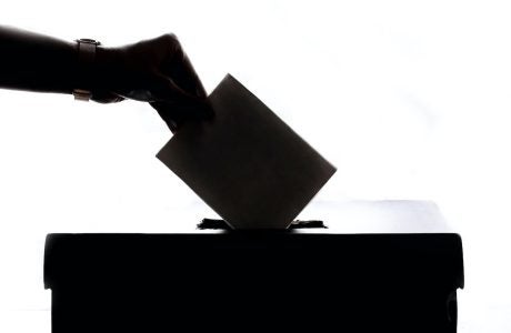 silhouette of hand placing ballot into box