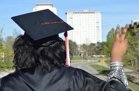 back of person wearing can and gown, outdoors