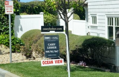For sale sign in a yard in front of a house