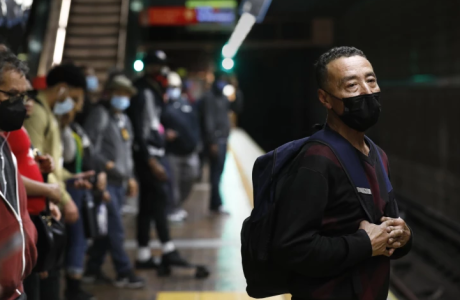 Man in a suit wearing a mask and carrying a backpack stands and waits for the Metro.
