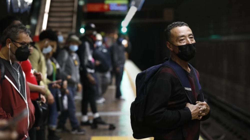 Man in a suit wearing a mask and carrying a backpack stands and waits for the Metro.