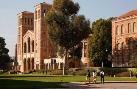 Three students walk across the parking lot on the UCLA campus in front of Royce Hall
