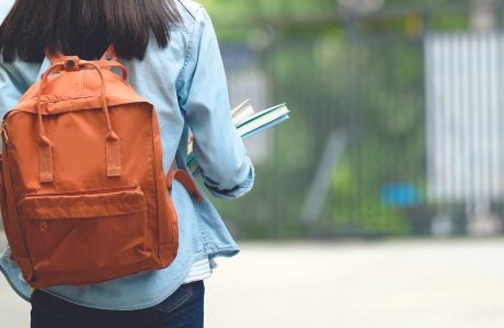 Back of student with backpack walking on street