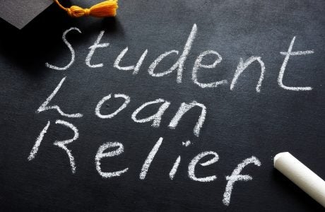 Student loan relief written on the blackboard and graduation cap.