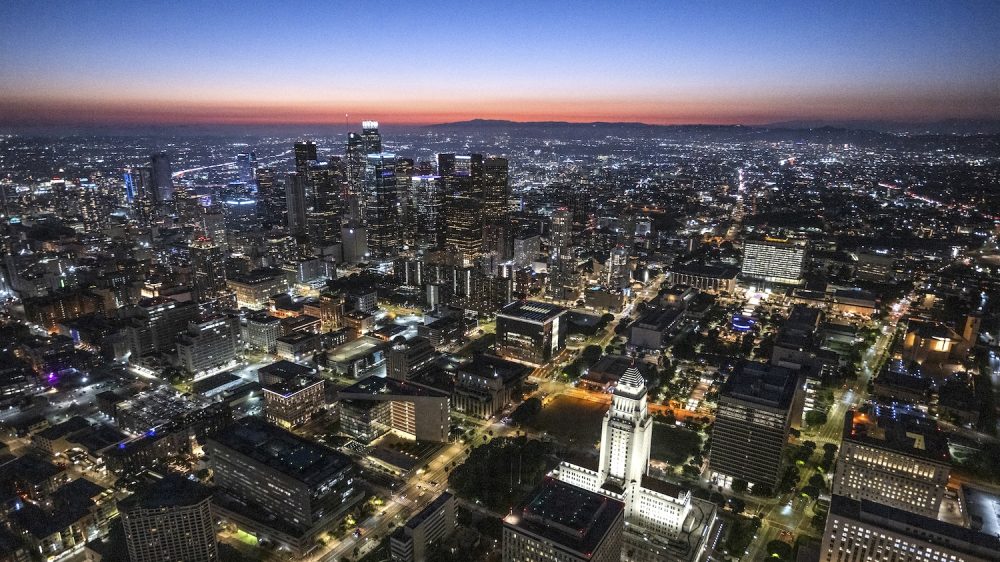 Downtown LA just after sunset during blue hour, captured from a helicopter point of view with lighted City Hall building.