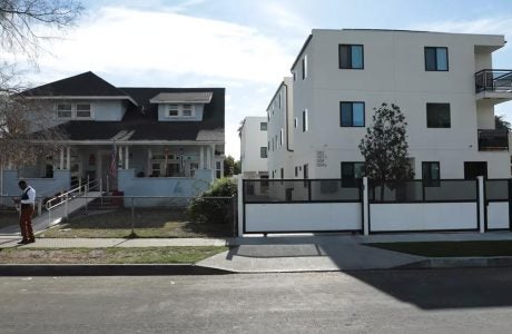 A single-story home sits next to a three-story apartment building